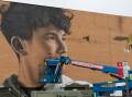 Bathurst artist Calum Hotham painting his Wallsend mural on the old Electrodry building. Picture Jonathan Carroll